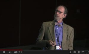Dr. Marsh on a dark stage with a microphone headset